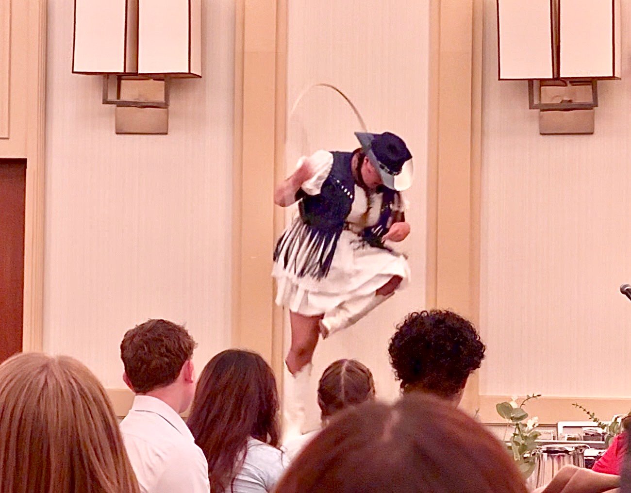 Kristen J. Lloyd jumping through a rope on stage during a resilience keynote